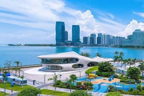 A waterfront property with a modern building, a swimming pool, and a view of a city skyline. - Homeinn · neo (Haikou Qilou Old Street Donghu Road) (Haikou)