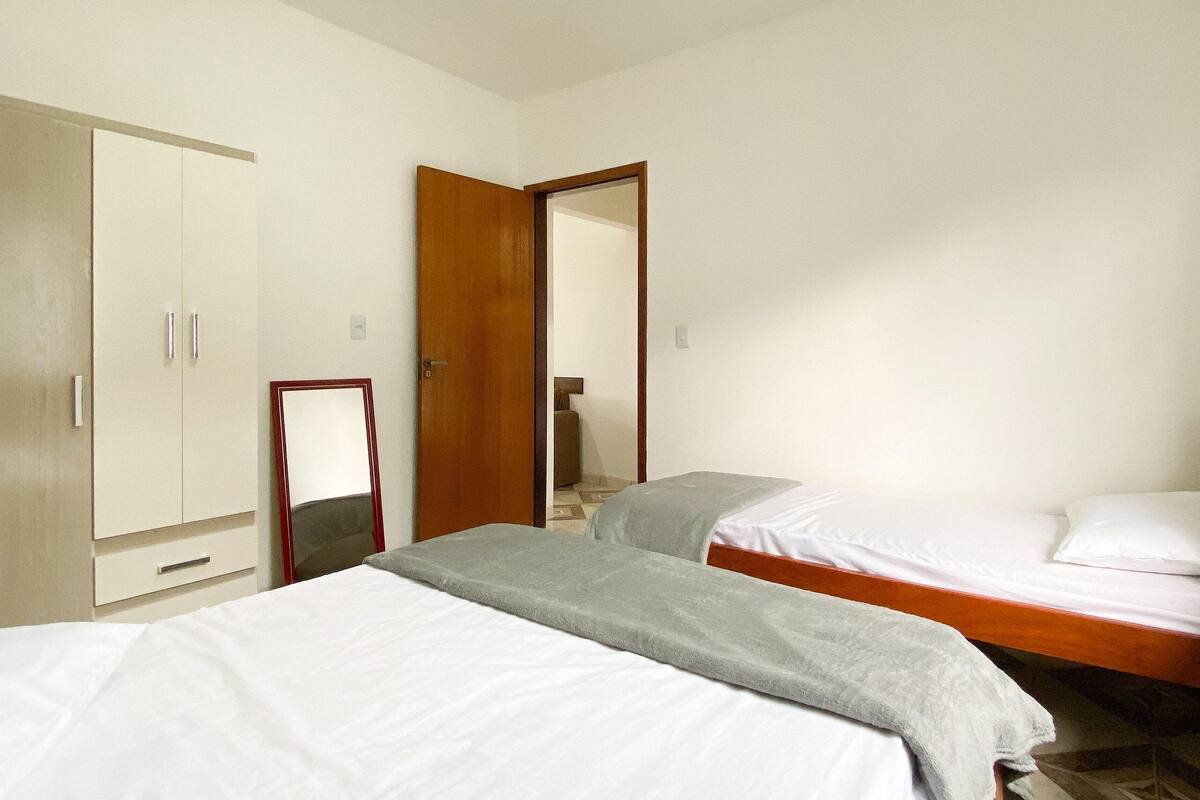 Un dormitorio con dos camas, un armario y un espejo.