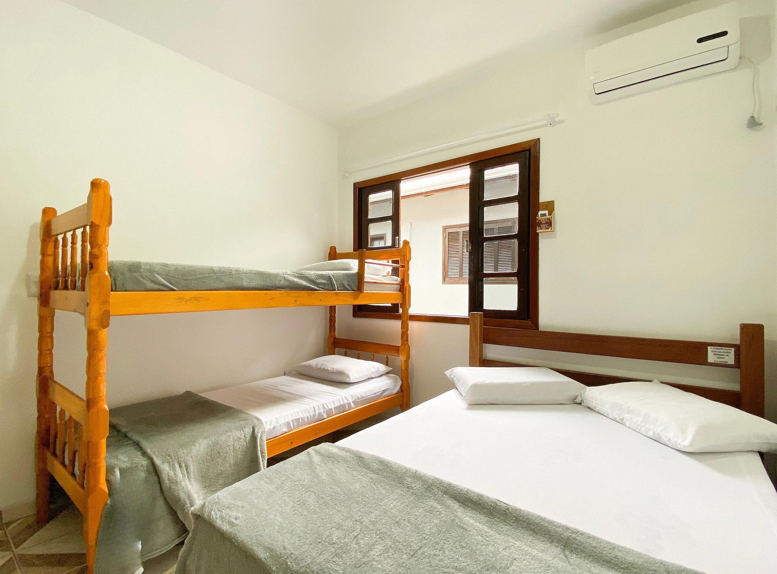 Un dormitorio con dos literas, una ventana con persianas y un equipo de aire acondicionado en la pared.