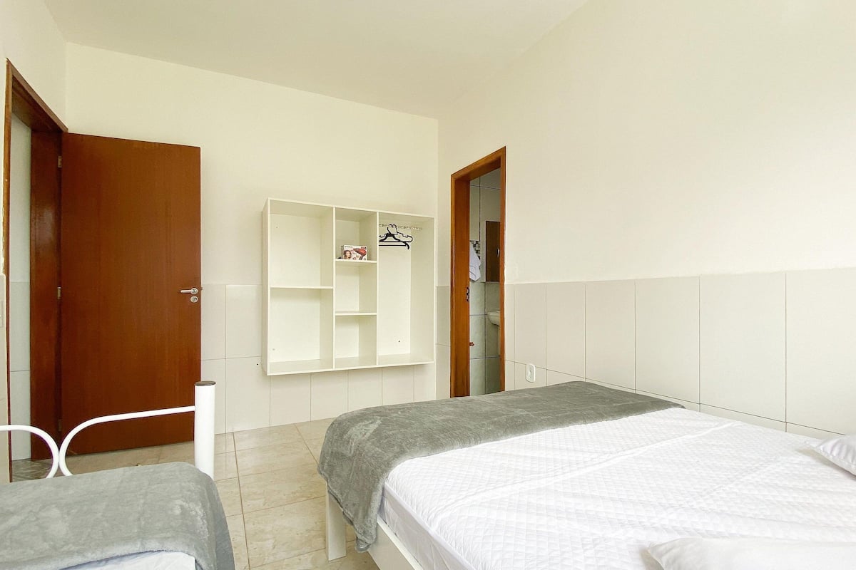 Un dormitorio con dos camas, un armario y un baño visible a través de una puerta abierta.