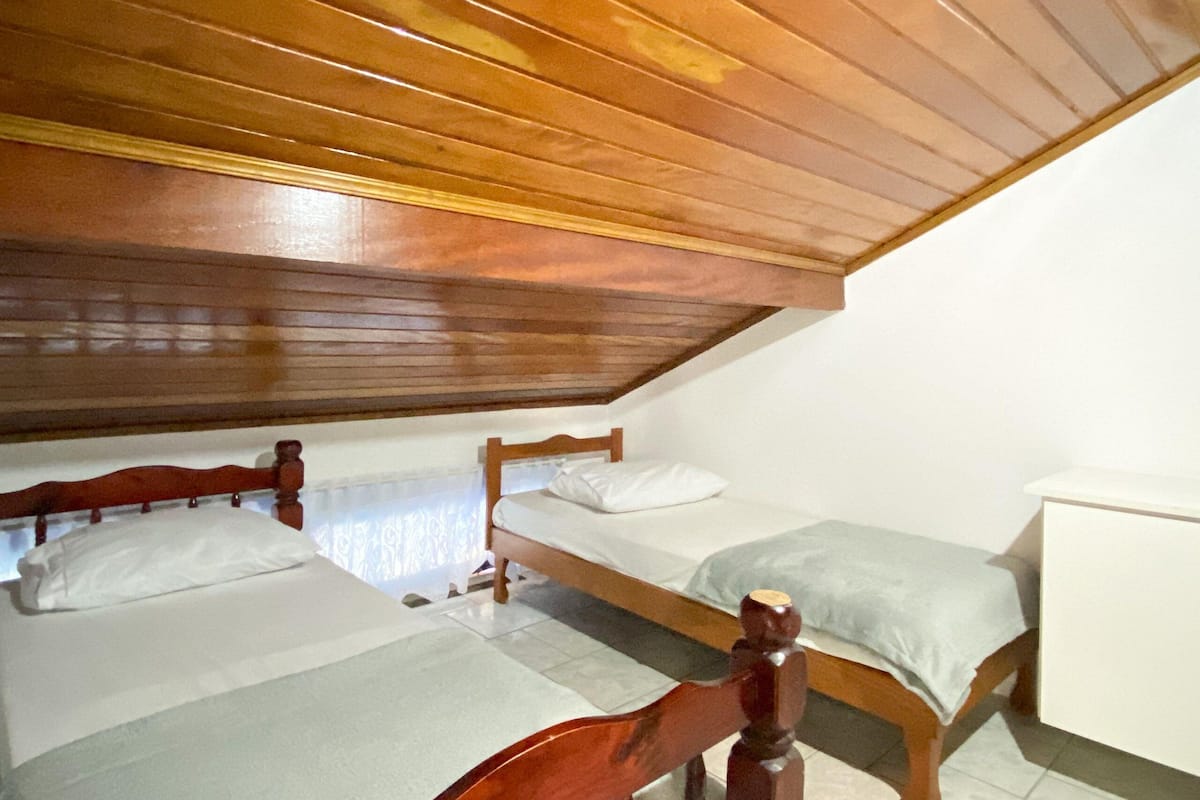 Una habitación pequeña y acogedora con dos camas de madera y techo inclinado.