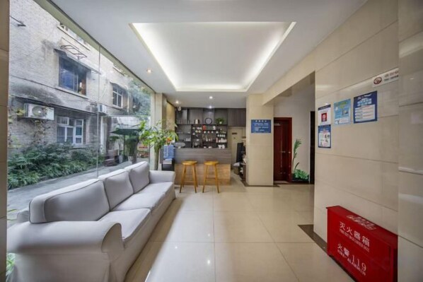 Un hall de hotel con recepción, un sofá y una zona de bar.