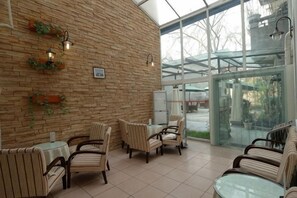 A cafe with brick walls, wicker furniture, and a glass door leading outside.
