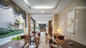 Un hall d’hôtel doté d’un long comptoir d’accueil, de plusieurs espaces aménagés avec des sièges et offrant une vue sur un jardin extérieur.
