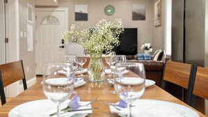 A dining table set with white plates, wine glasses, and a vase with white flowers.