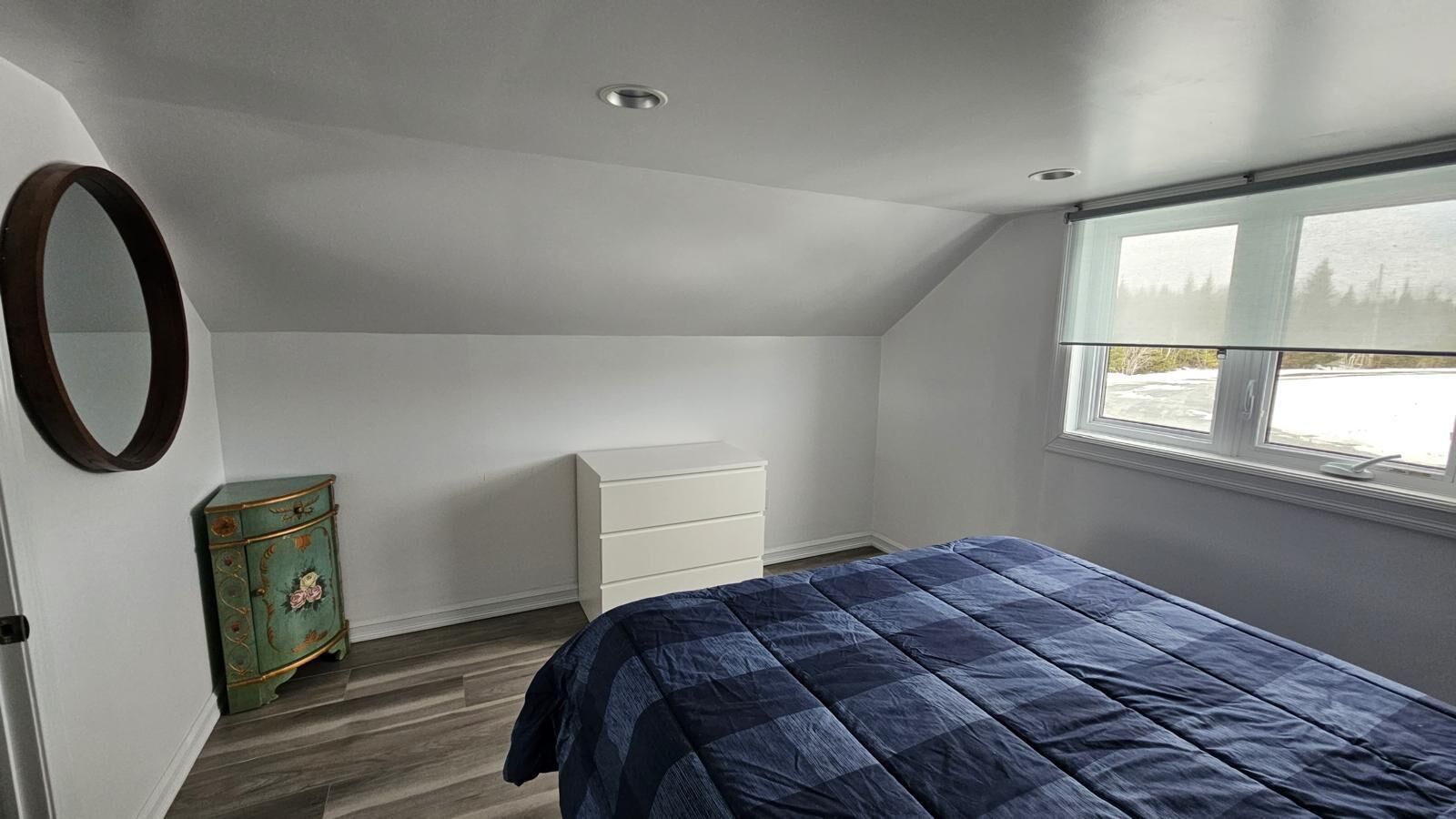 Un dormitorio con cama, cómoda, tocador y ventana con vistas.
