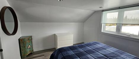 Un dormitorio con cama, cómoda, tocador y ventana con vistas.