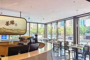 Un interior moderno con una recepción, zona de estar y amplios ventanales con vistas a la calle.