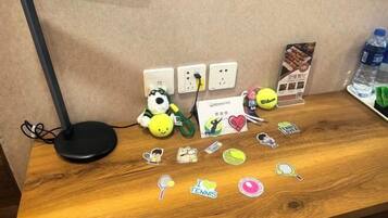 Uma mesa de madeira com uma lâmpada, um brinquedo de pelúcia, uma bola de tênis e diversos adesivos.
