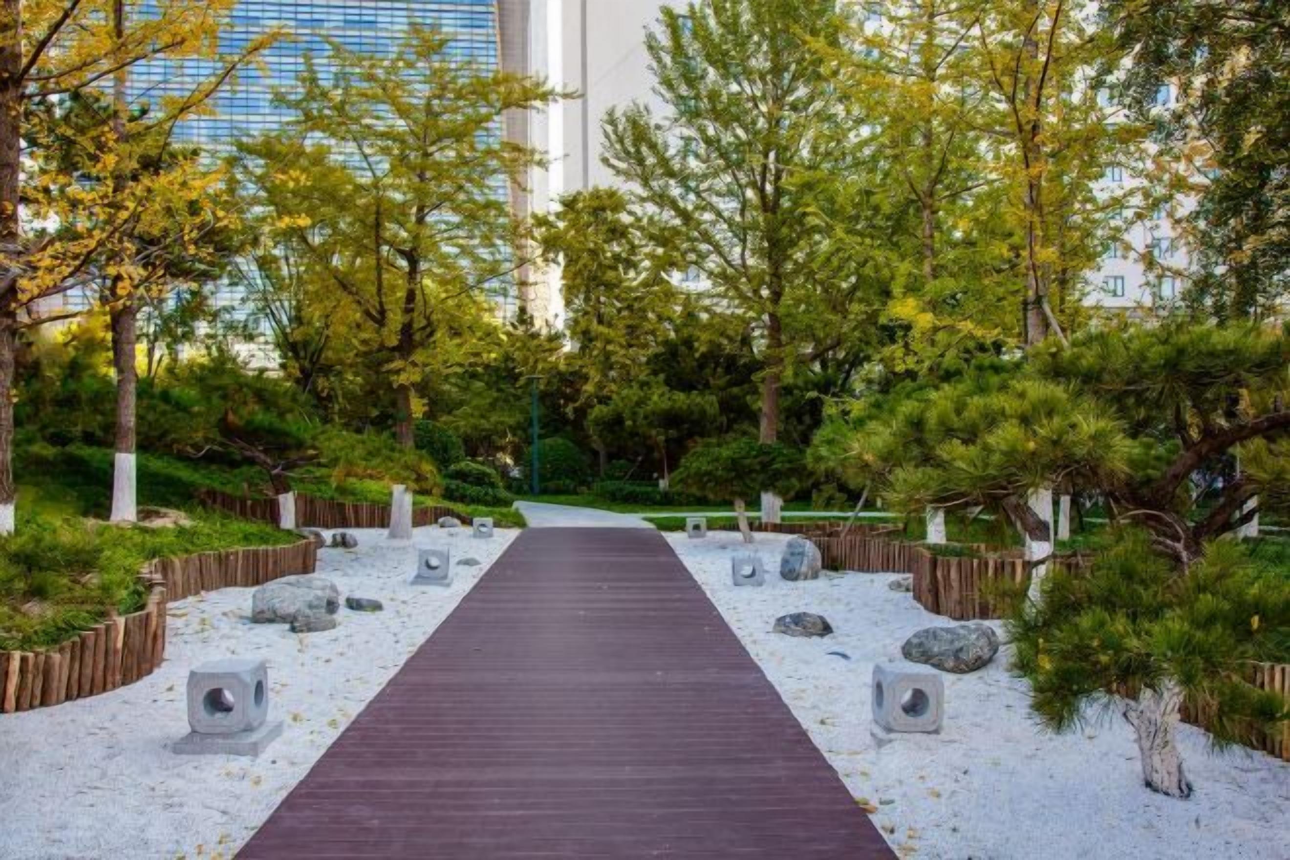 A pathway leading through a landscaped garden with trees and rocks.