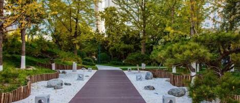 A pathway leading through a landscaped garden with trees and rocks.