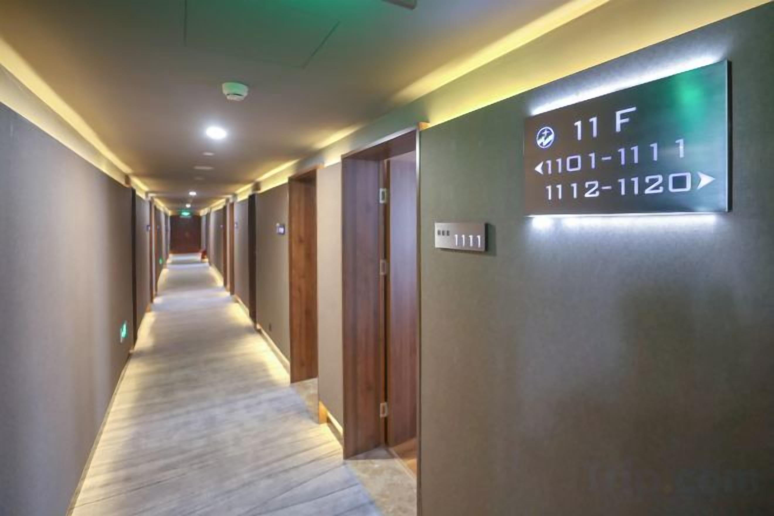Pasillo de hotel con puertas numeradas y un letrero que indica la habitación 11F.