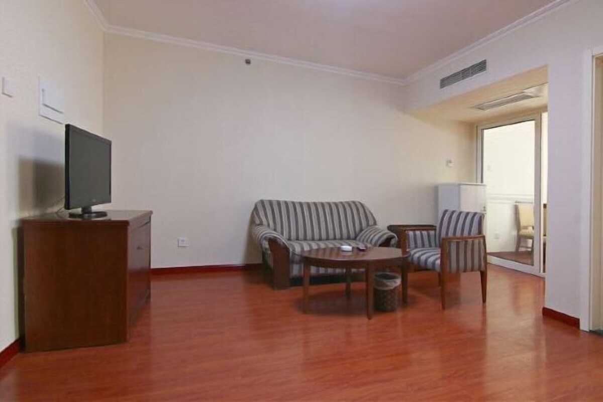A living room with a sofa, armchairs, a coffee table, and a TV on a stand.