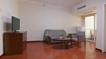 Uma sala de estar com sofá, poltronas, mesa de centro e televisão em um móvel.
