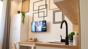Een moderne keuken met een ingebouwde televisie, een houten eettafel en een witte kast.