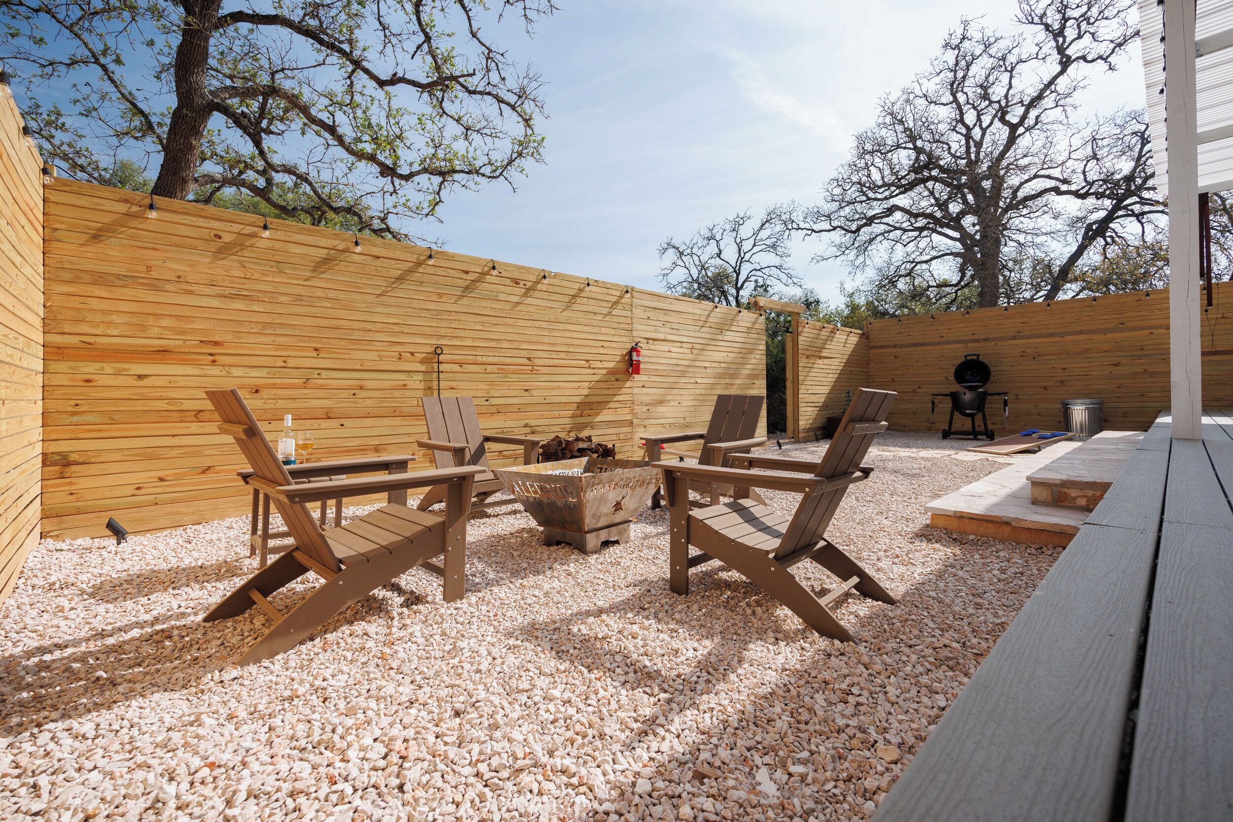 Un patio exterior con mobiliario de madera, una chimenea y una parrilla.