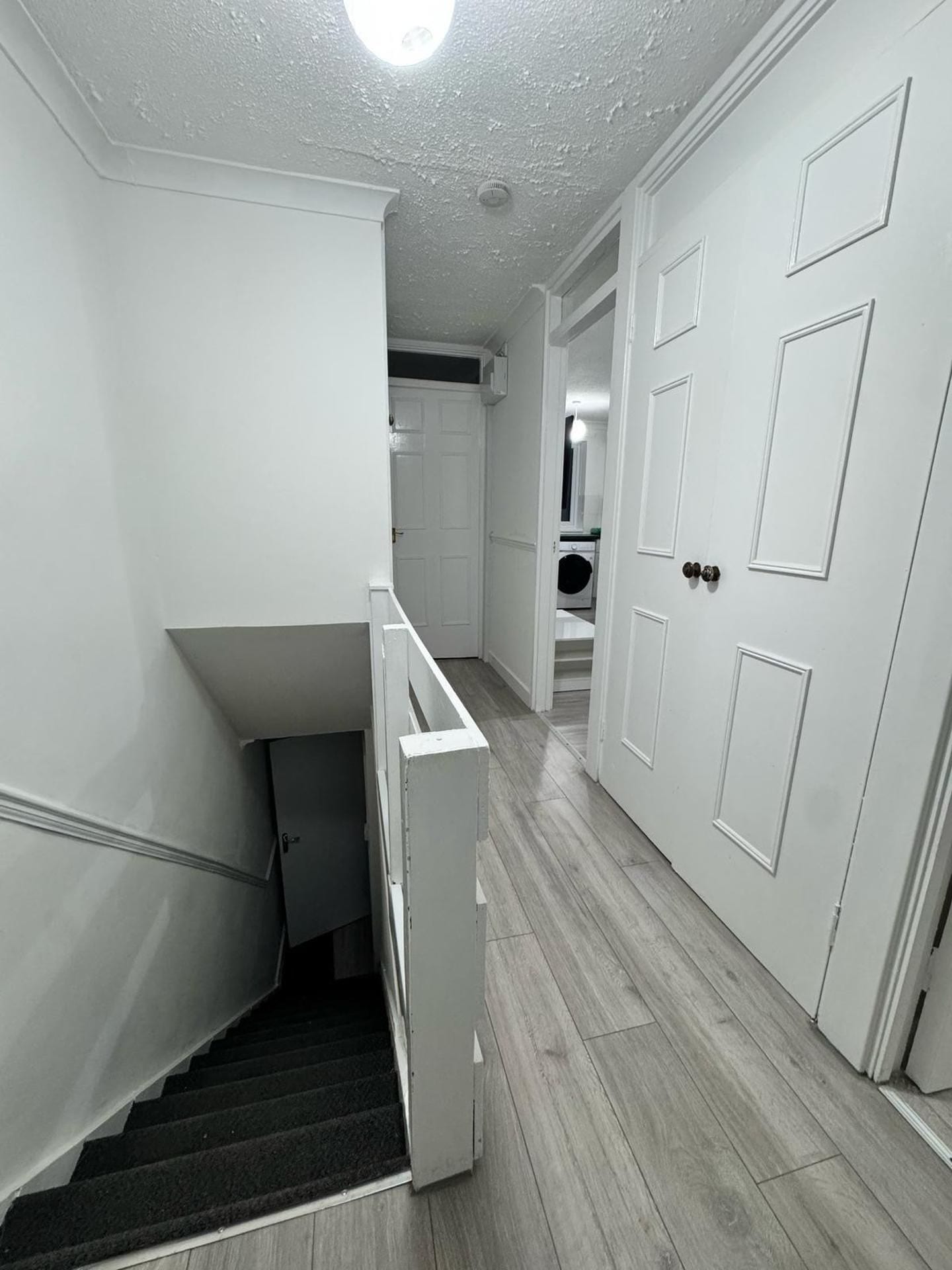 Un pasillo con una escalera que lleva a un cuarto de lavandería.