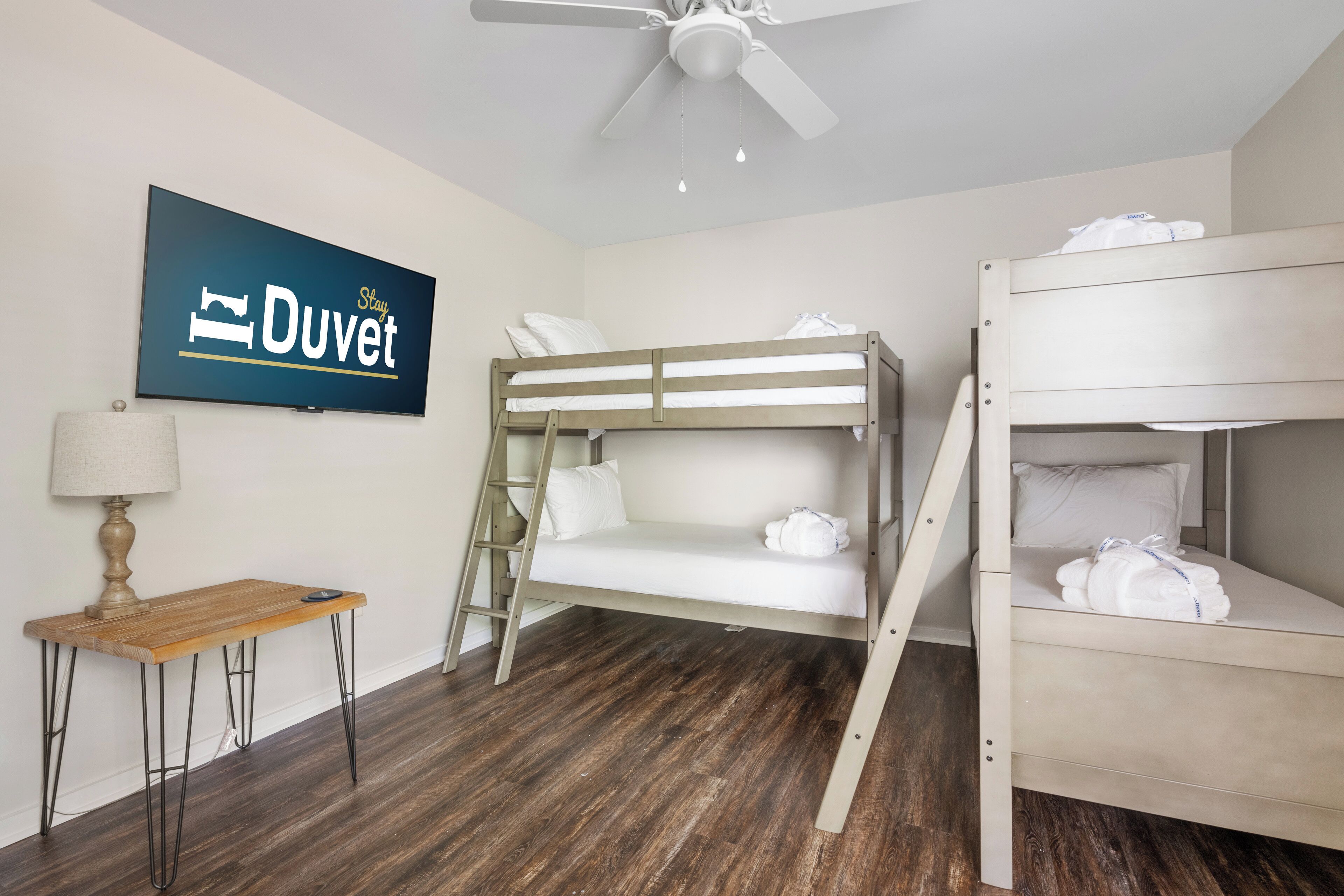 Ein Zimmer mit einem Etagenbett, einem Schreibtisch, einer Leiter, einem Deckenventilator und einem Schild an der Wand.