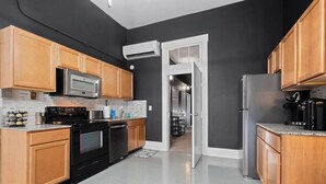 A modern kitchen with wooden cabinets, a stainless steel refrigerator, a microwave, and a black stove. - Spacious Luxury Black Downtown Apartment - Minutes from WEC! (Wilmington)