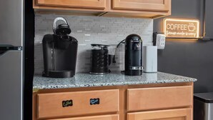A kitchen with wooden cabinets, a granite countertop, and three coffee makers. - Spacious Luxury Black Downtown Apartment - Minutes from WEC! (Wilmington)