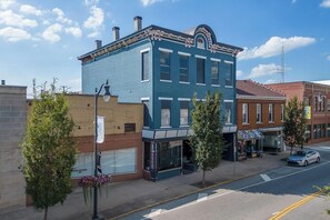 A two-story building with a blue facade, a corner entrance, and a small storefront on the ground floor.