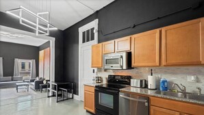 A modern kitchen with wooden cabinets, stainless steel appliances, and a large window. - Spacious Luxury Black Downtown Apartment - Minutes from WEC! (Wilmington)