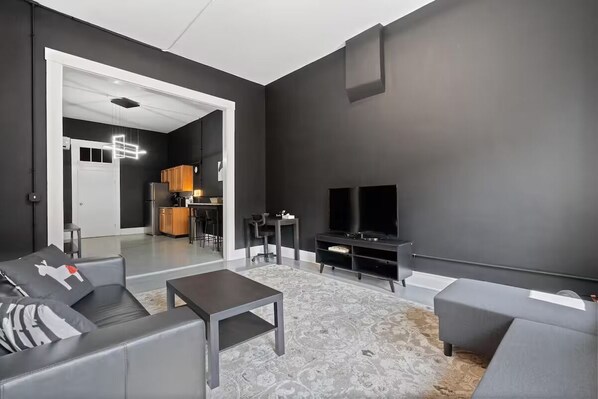 Un salon moderne avec un canapé gris, une table basse et un téléviseur à écran plat.