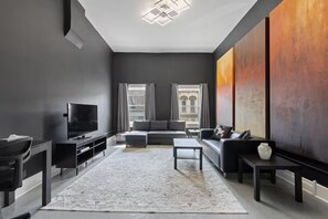 Un salon moderne avec une grande télévision, un canapé, une table basse et un tapis.