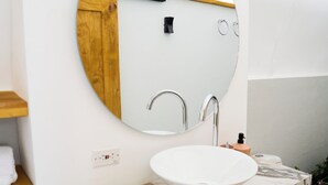 A modern bathroom with a round mirror, white sink, and wooden shelves. - Glamping altos de la rivera (Jenesano)
