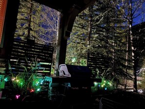 Un espace extérieur abrité, doté d’un panneau indicateur, entouré d’arbres et agrémenté de plantes illuminées.