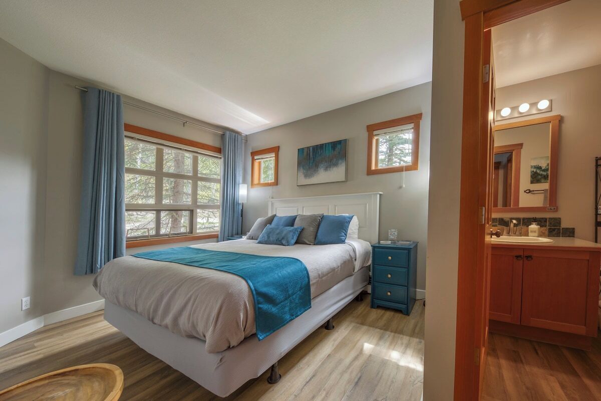 A bedroom with a bed, bedside table, and a bathroom with a vanity and mirror.