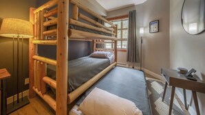 A bunk bed room with a desk and lamp.