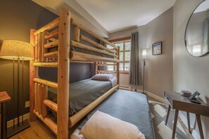 Une chambre avec un lit superposé, un bureau et une lampe.