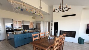 A spacious kitchen with a central island, a dining area with wooden chairs, and a fireplace. - Casa Trè Fari - Holiday home in Corsica with sea view (Porto-Vecchio)