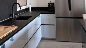 A modern kitchen with a stainless steel refrigerator, a black countertop, and a wall-mounted air purifier. - Casa Trè Fari - Holiday home in Corsica with sea view (Porto-Vecchio)