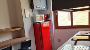 A compact kitchen with a red refrigerator, a microwave, a sink, and a window providing natural light. - Accommodation Salerno Gateway Amalfi Coast (Salerno)