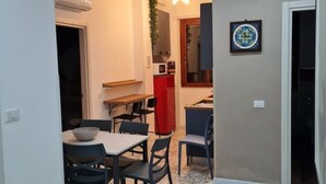 A compact dining area with a table and chairs, a red cabinet, and a small kitchen area with a microwave and sink. - Accommodation Salerno Gateway Amalfi Coast (Salerno)