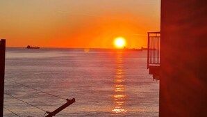 A sunset over a calm sea with a distant ship and a balcony overlooking the water. - Accommodation Salerno Gateway Amalfi Coast (Salerno)