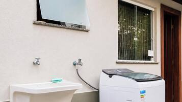 A laundry area with a washing machine and a sink mounted on the wall.