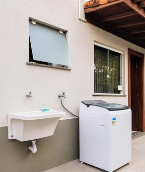 Un espace buanderie équipé d’un lave-linge et d’un évier fixé au mur.
