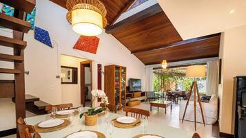 A dining area with a white table set for four, surrounded by wooden chairs.