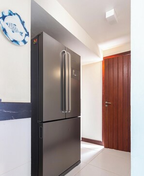 Un réfrigérateur en acier inoxydable dans une cuisine avec une porte en bois et une décoration murale bleue et blanche.
