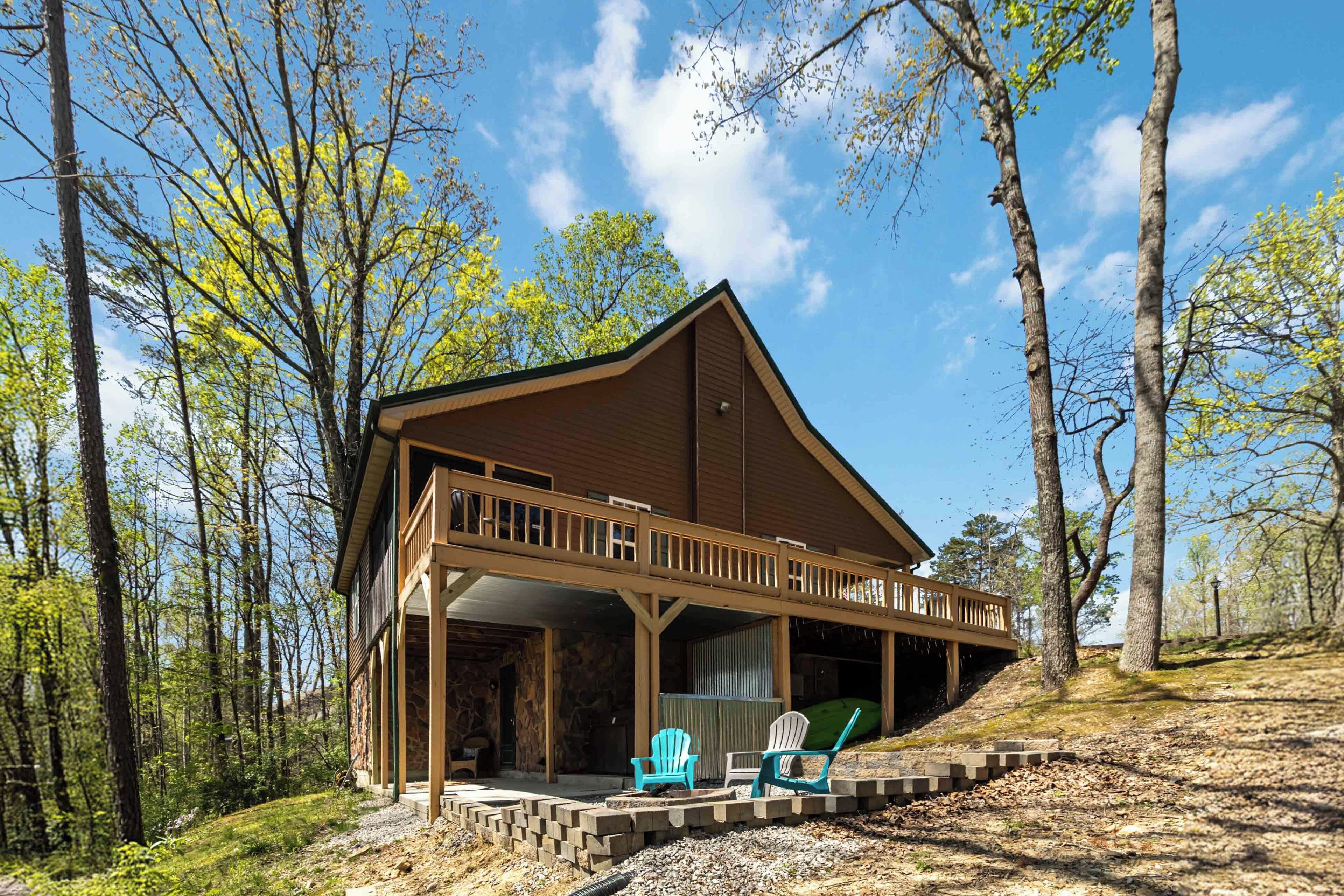 Une cabane dotée d’un porche couvert, de deux fauteuils Adirondack et de fondations en pierre.