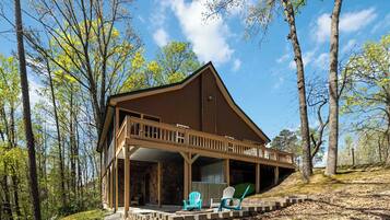 Une cabane dotée d’un porche couvert, de deux fauteuils Adirondack et de fondations en pierre.