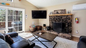 Una sala de estar con chimenea de piedra, un televisor montado en la pared, un sofá cómodo y una mesa de centro.
