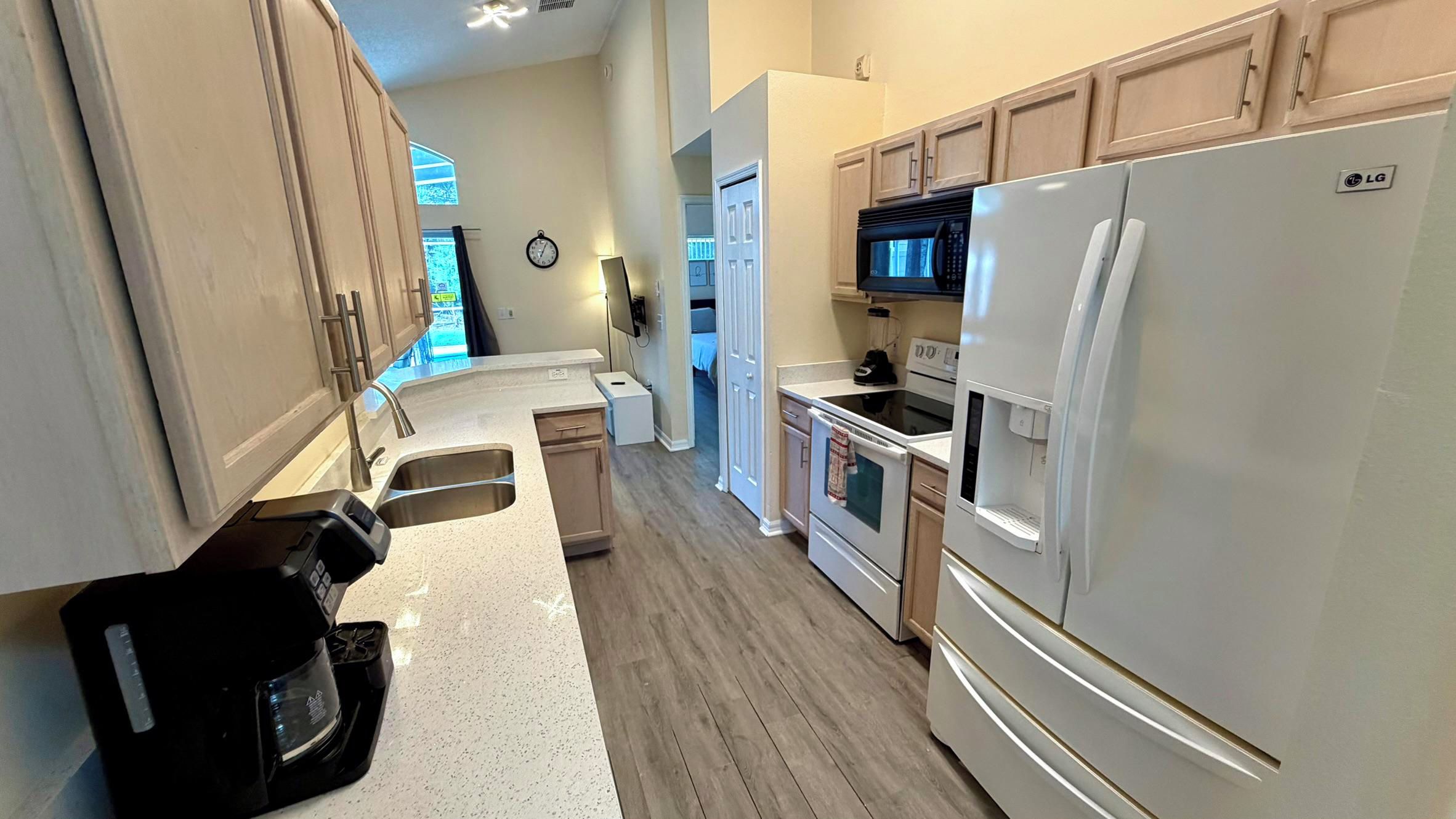 A kitchen with a refrigerator, stove, microwave, and a coffee maker.