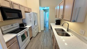 A compact kitchen with a microwave, toaster, refrigerator, stove, and sink.