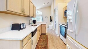 A compact kitchen with wooden cabinets, a white countertop, a toaster, a sink, and a refrigerator.
