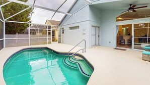 An indoor swimming pool with a glass ceiling, a ceiling fan, and a view of the outside.