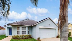 A single-story house with a garage, a front lawn, and a palm tree.